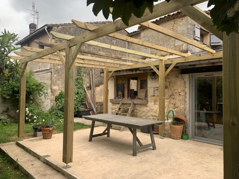 Une pergola en bois finalisée, offrant un espace de détente couvert dans un jardin. ​​