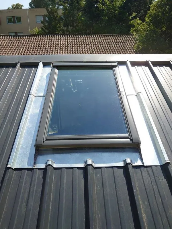 Fenêtre de toit Velux installée sur une toiture en bac acier pour apporter luminosité et ventilation à l’intérieur.