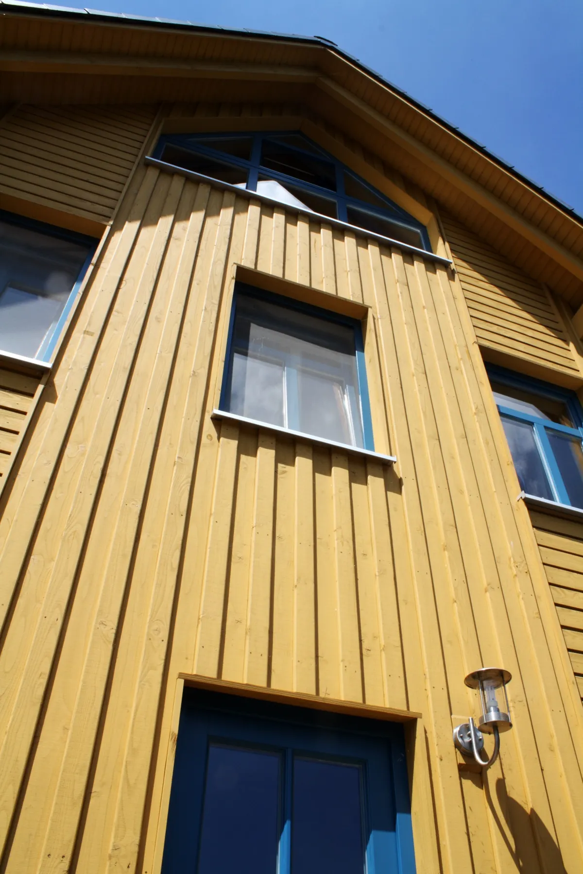 Façade de bâtiment isolée avec un bardage vertical en bois coloré pour une finition esthétique unique.
